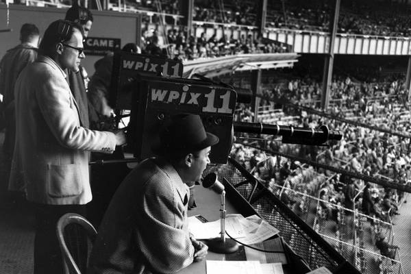 Yankees announcer Mel Allen calls the game against the Orioles from the television box behind home plate at Yankee Stadium on May 11, 1956.