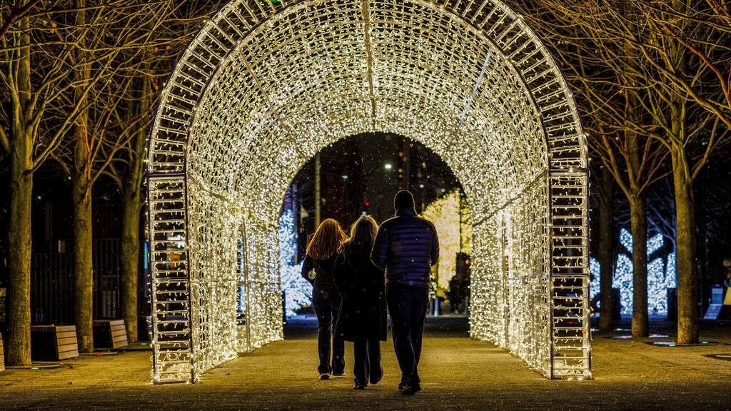 Snow falls as people walk past holiday displays during Light Up the Lake at Navy Pier in Chicago on November 27, 2023.