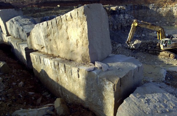An excavator was working at the Independent Limestone Company quarry in Bloomington, Indiana, where the Pentagon's replacement stone came from in 2002.  The limestone is then transported by truck to Bybee Stone Company in Bloomington, Indiana, where it is processed into finished limestone blocks and shipped to Washington, D.C., to repair damage to the Pentagon on September 11, 2001.  This particular company was not the original source of the stone for the Pentagon, but the original company, which is still in operation, no longer has the old-fashioned saw that gives the stone its distinctive appearance.  Tribune photo: Bonnie Trafelet