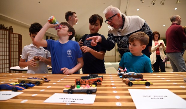 Mike McCauley of Winnetka, top right, on the stage shelf, looking at the cars with other derby fans before the race, at the Cub Scout Pack 18 Pinewood Derby at Winnetka Presbyterian Church (1255 Willow Road) on Jan. 31, 2024 in Winnetka.
