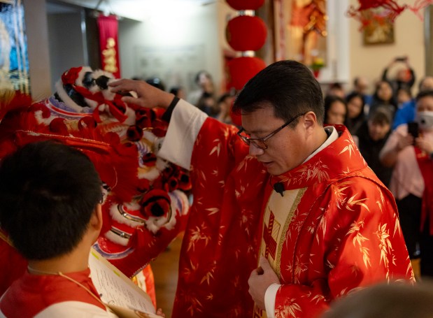 Father Frances Li, St.  Therese blesses the lion as the Chinese Catholic Church celebrates the Lunar New Year during mass on February 11, 2024.  (Brian Cassella/Chicago Tribune)
