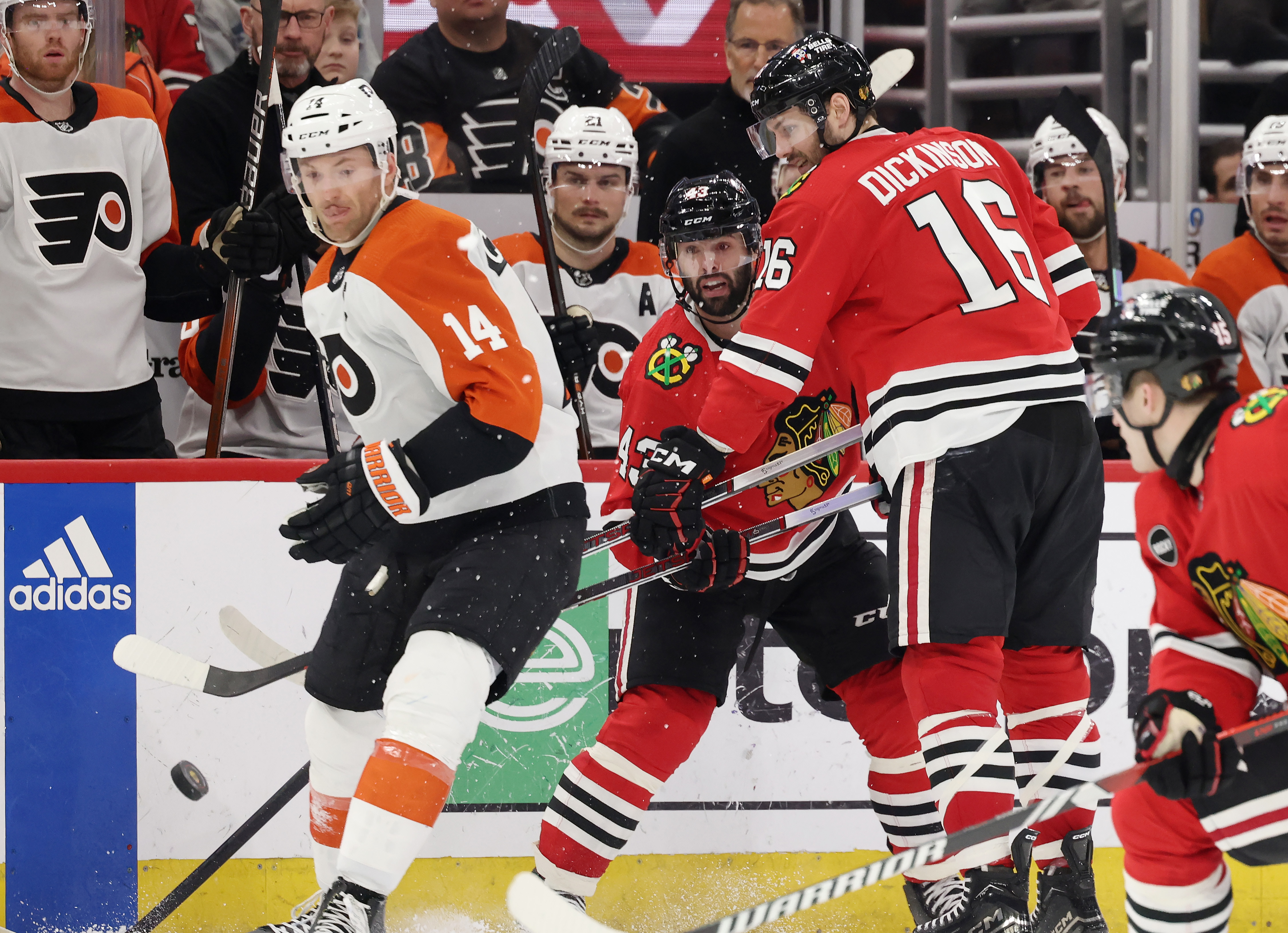 The puck passes Flyers center Sean Couturier (14) and Blackhawks center Colin Blackwell (43) in the third period on Feb. 21, 2024, at the United Center in Chicago.  (John J. Kim/Chicago Tribune)