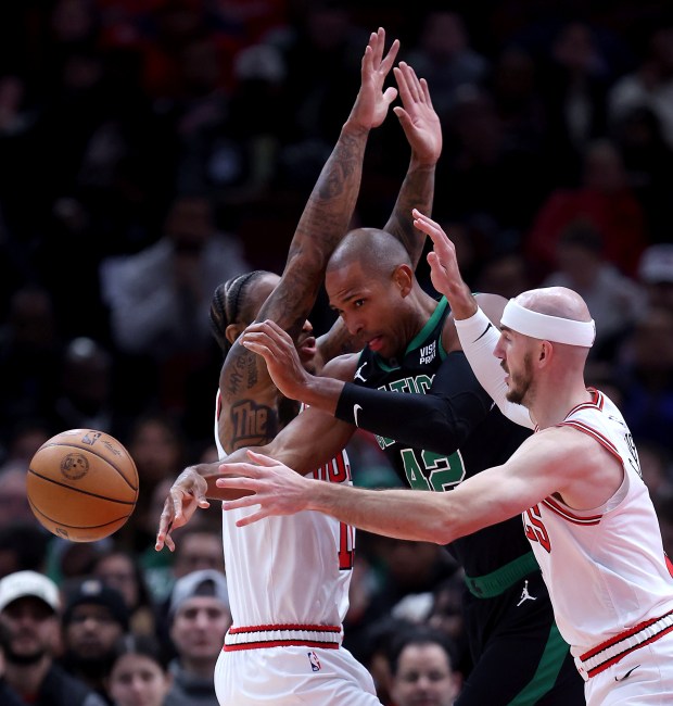 Celtics center Al Horford passes the ball between Bulls forward DeMar DeRozan (left) and guard Alex Caruso at the United Center on February 22, 2024.