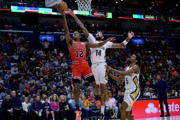Chicago Bulls guard Ayo Dosunmu (12) shoots at New Orleans Pelicans forward Brandon Ingram (14) during the first half of an NBA basketball game in New Orleans on Sunday, February 25, 2024.  (AP Photo/Matthew Hinton)