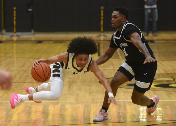 Mount Carmel's Noah Mister (2) lost his footing after being fouled by Hyde Park's Germaine Benson (11) during the Class 3A Hinsdale South Regional semifinals on Tuesday, Feb. 27, 2024, in Darien, IL.  (Steve Johnston/Daily Southtown)
