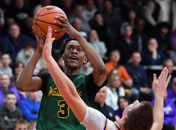 Waubonsie Valley's Tre Blissett (3) drives to the basket after Downers Grove North's Jack Stanton falls in front of him during the Class 4A East Aurora Regional semifinal game in Aurora on Wednesday, Feb. 28, 2024. (Jon Cunningham for the Naperville Sun)