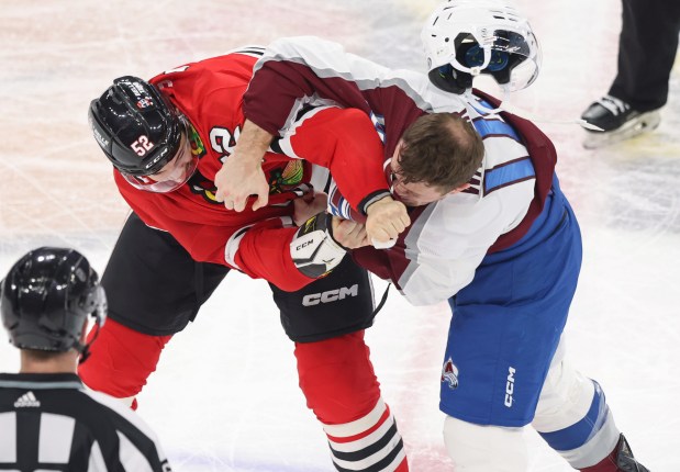 Avalanche right wing Chris Wagner's helmet flies off as he tackles Blackhawks center Reese Johnson in the second period at the United Center on Feb. 29, 2024.  (John J. Kim/Chicago Tribune)
