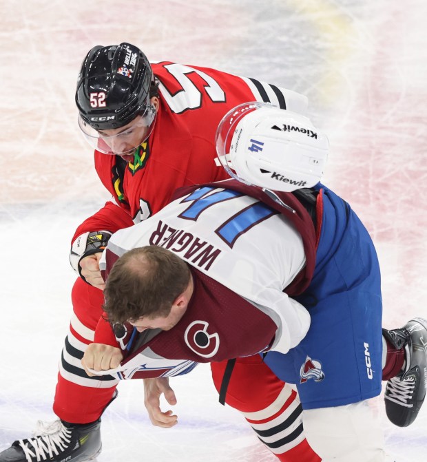 Avalanche right wing Chris Wagner's helmet flies off as he tackles Blackhawks center Reese Johnson (52) in the second period at the United Center on Feb. 29, 2024.  (John J. Kim/Chicago Tribune)