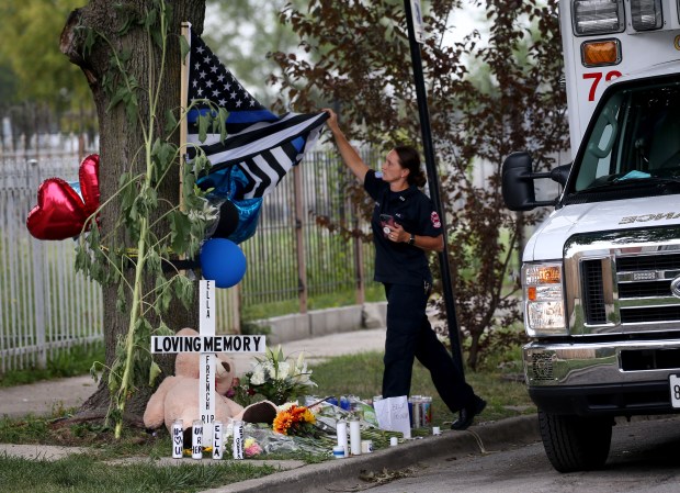 A Chicago Fire Department paramedic unfurls a flag at a memorial service for Chicago police Officer Ella French in the 6300 block of South Bell Avenue, Aug. 10, 2021. (Antonio Perez/Chicago Tribune)
