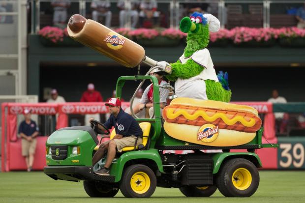 FILE - Phillie Phanatic comes out with his Hot Dog Launcher during the fifth inning of a baseball game between the Atlanta Braves and Philadelphia Phillies on Monday, July 4, 2016 in Philadelphia.  For more than a quarter-century, Phillies fans thought dollar hot dog night was the best ballpark promotion, but the team has now decided it's the best hot dog.  (AP Photo/Chris Szagola, File)