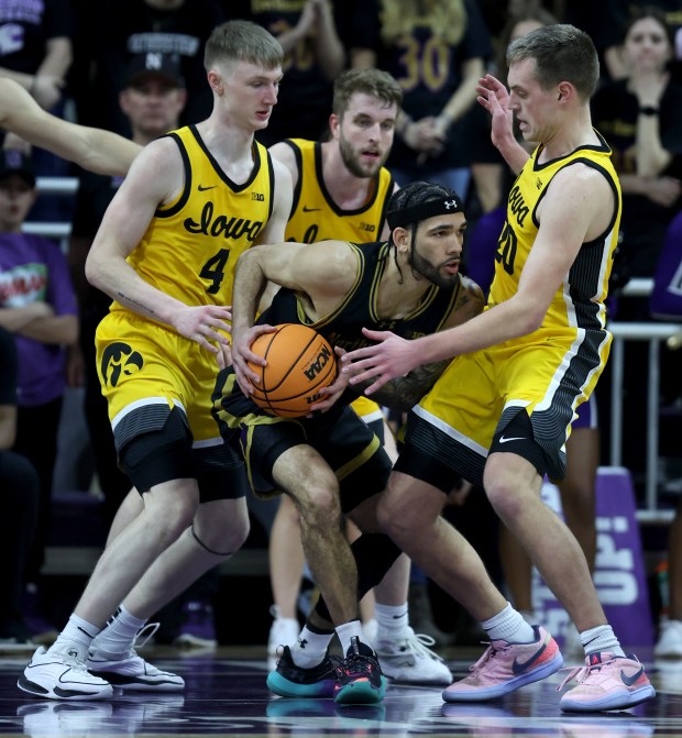 Northwestern guard Boo Buie (0) looks for an open teammate as Iowa players surround him during the second half of a game at Welsh-Ryan Arena in Evanston on March 2, 2024.  (Chris Sweda/Chicago Tribune)