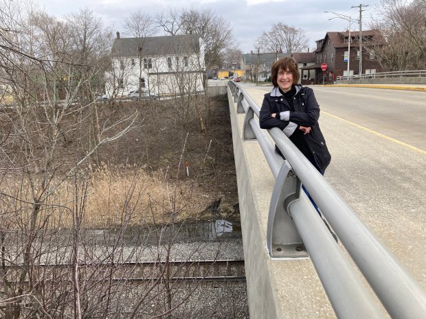 Christina Holston, president of the Monee Historical Society, stands on the Main Street bridge in Monee on Feb. 27, with the village's two historic buildings in the background.  One is being converted into a private residence and the other into a coffeehouse.  (Paul Eisenberg/Daily Southtown)