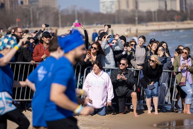 Spectators watch participants dive into Lake Michigan on a warm morning during the 24th Annual Chicago Polar Plunge at North Avenue Beach on Sunday, March 3, 2024.  (Brian Cassella/Chicago Tribune)