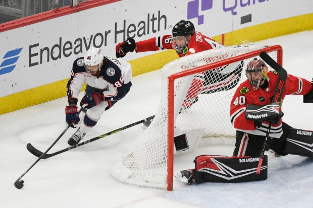 Columbus Blue Jackets' Kirill Marchenko (86) moves the puck against Chicago Blackhawks' Louis Crevier (46) and goaltender Arvid Soderblom (40) during the second period of an NHL hockey game in Chicago on Saturday, March 2, 2024.  (AP Photo/Paul Beaty)