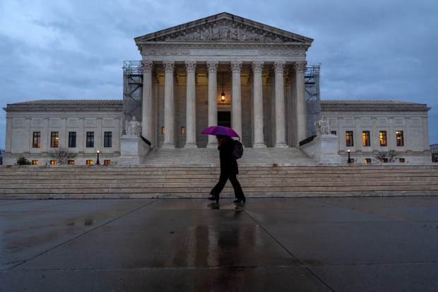 A woman under a purple umbrella walks past the Supreme Court in Washington on February 28, 2024.(Jacquelyn Martin/AP)