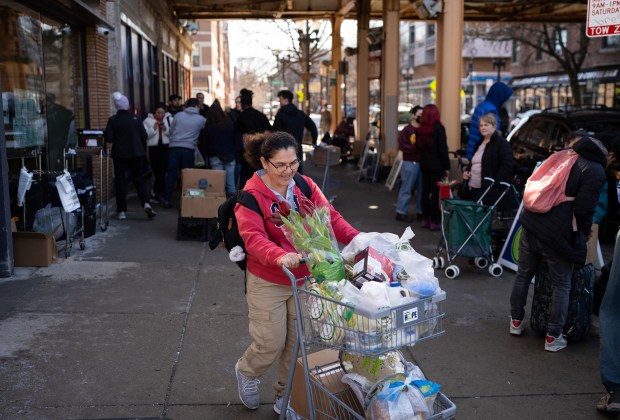Vicenta Buitrago leaves the Nourishing Hope-Sheridan Market with her food products on Monday, February 26, 2024.  Food pantries in Chicago are struggling to keep up with demand due to the influx of immigrants coming to the city.  (E. Jason Wambsgans/Chicago Tribune)
