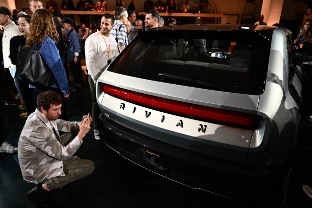 Attendees watch the new Rivian R3 electric vehicle at the Rivian South Coast Theater on March 7, 2024 in Laguna Beach, California.  (Patrick T. Fallon/AFP-Getty Images)