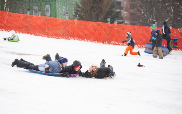 While adults dug into the moving snow in Naperville Friday night, kids hit the sledding hill at Rotary Park.  Riley Howard, 17, left, Morgan Maher, 18, center, and Michelle Jurec, 18, right, took advantage of the break from the storms to enjoy the wintry conditions.
