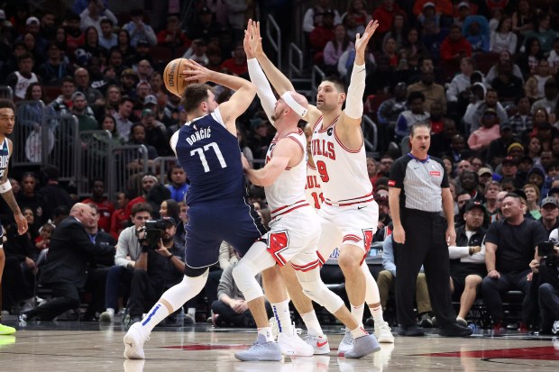 Mavericks guard Luka Doncic (77), Bulls guard Alex Caruso (6) and Bulls center Nikola Vucevic (9) look to pass while defending during the first half at the United Center in Chicago on March 11, 2024.  (Terrence Antonio James/Chicago Tribune) )