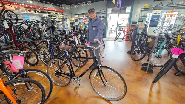 Mike Farrell, owner of Prairie Path Cycles in Batavia, shows off a retro bike, complete with fenders and chain guard.  He said the bike reflects the many bike options buyers have today.  (For David Sharos/Beacon News)